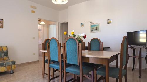 a dining room with a table and chairs and a television at Appartamenti Torre Suda by Salento Affitti in Torre Suda