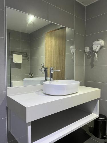 a bathroom with a white sink and a mirror at White Lodge in Pantai Cenang