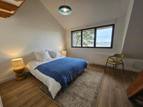 a bedroom with a bed with a blue comforter and a window at Ker Ty Mor - Waterfront Family House in Port-Louis