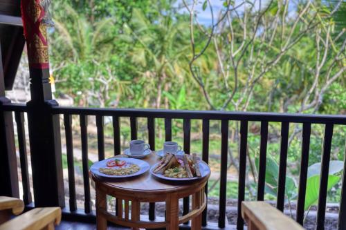 una mesa con 2 platos de comida en el balcón en Kelingking Terrace Cottage, en batumadeg