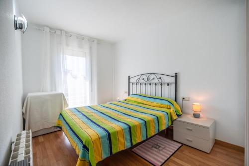 a small bedroom with a bed with a striped blanket at Imperatore Apartment in Cunit