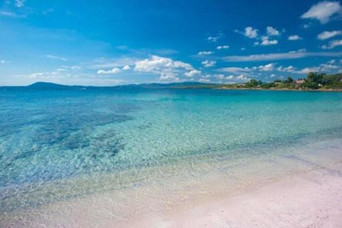 a large body of water with sand and the ocean at Tina's Tiny House - 10 meters from the beach in Olbia