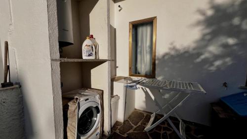 a laundry room with a washing machine and a window at Tina's Tiny House - 10 meters from the beach in Olbia