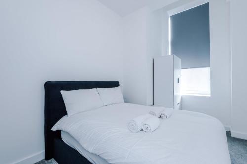 a white bed with two towels on top of it at Cohost Partners Cozy Stay Heart of Warrington in Warrington