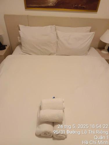 Una cama con almohadas blancas y toallas. en Starlight Hotel25, en Ho Chi Minh