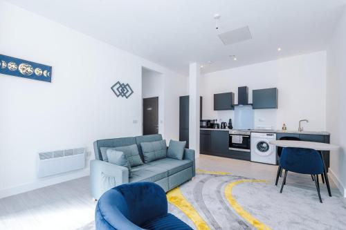 a living room with a blue couch and a kitchen at Cohost Partners Cozy Stay Heart of Warrington in Warrington