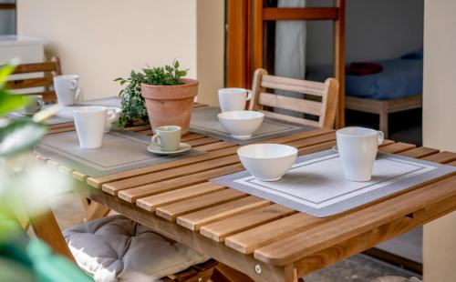 a wooden table with bowls and cups on it at Modern Beach Apartment Near Forte dei Marmi in Marina di Massa