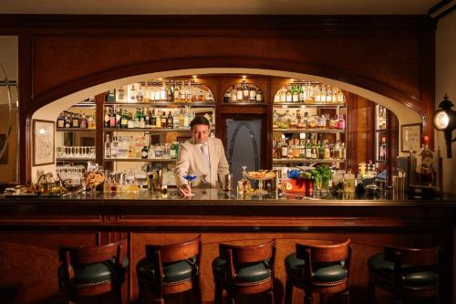 a man standing behind a bar in a pub at Grand Hotel Villa Serbelloni - A Legendary Hotel in Bellagio