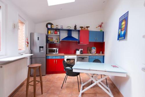 une cuisine avec des armoires rouges et bleues et une table dans l'établissement Maison Bleu, à Honfleur