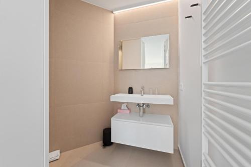 Un baño con un lavabo blanco y un espejo. en Luxueus en smaakvol prive appartement Sint-Idesbald, en Koksijde