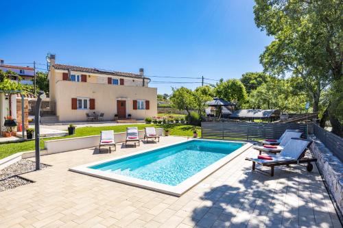 a swimming pool with chairs and a house at Villa Fuma up to 6 persons with private pool & sea view in Central Istria in Bale