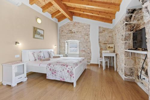 a bedroom with a white bed and a stone wall at Villa Fuma up to 6 persons with private pool & sea view in Central Istria in Bale