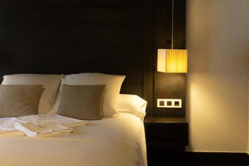 a bed with white sheets and a lamp next to it at La Plaza in Hervás