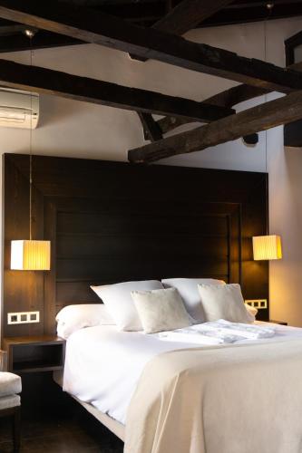 a bedroom with a large bed with white sheets and pillows at La Plaza in Hervás
