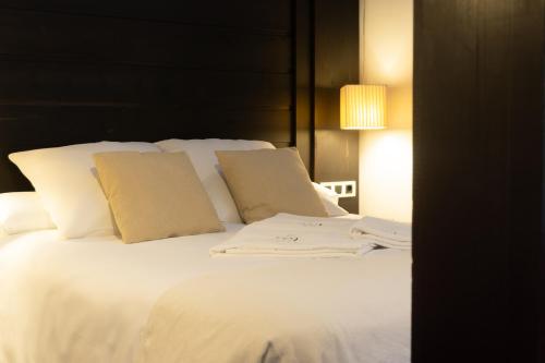 a large bed with white sheets and pillows at La Plaza in Hervás
