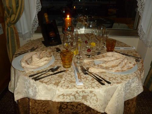 a table with a white table cloth with plates and silverware at Hotel Cima d'Oro in Ledro