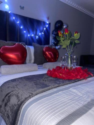a bed with a table with red flowers and balloons at Homely Palace Guesthouse in Midrand
