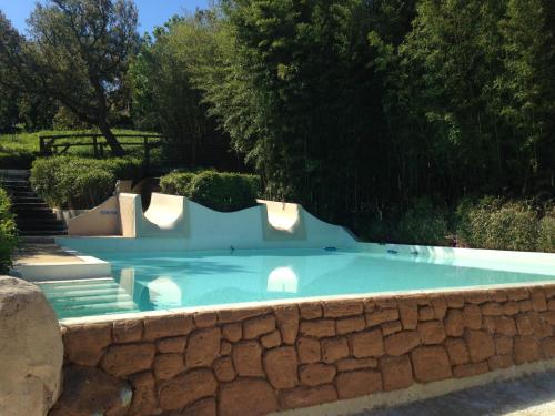una piscina con un muro di pietra intorno di Appartement Les Restanques du Golfe de Saint-Tropez a Grimaud