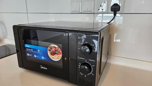 a black microwave with a pizza on top of it at Newly Furnished Home! TrivesHome GM Aeon Port Klang in Klang