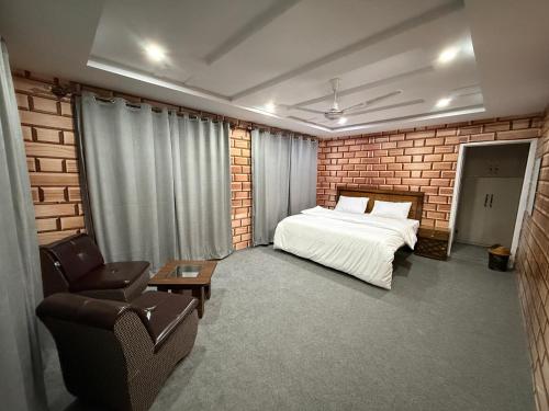 ein Schlafzimmer mit einem Bett, einer Couch und einem Stuhl in der Unterkunft Qasr اشرف in Skardu
