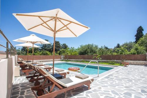 a swimming pool with lounge chairs and an umbrella at Oasis Luxury Villa in Rhodes Town