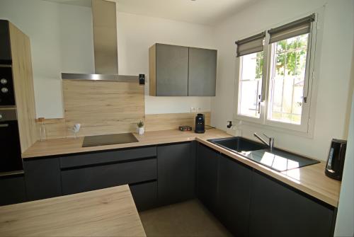 d'une cuisine avec des placards noirs, un évier et une fenêtre. dans l'établissement Charmante maison de ville avec jardin, à Montélimar