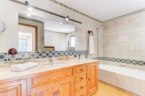 a bathroom with a sink and a tub and a mirror at Villa Can March by Villa Plus in Cala de Sant Vicenc