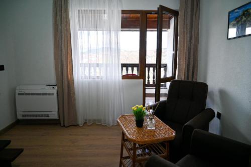 a living room with a chair and a table and a window at Къща Джано in Dobrinishte