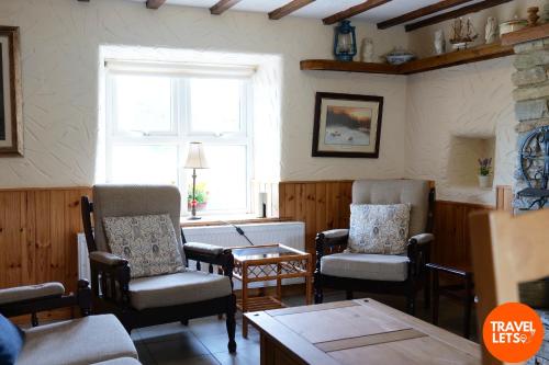 a living room with chairs and a table and a window at 5BR Farmhouse By Travel Lets Holiday Rentals Donegal in Carrigart