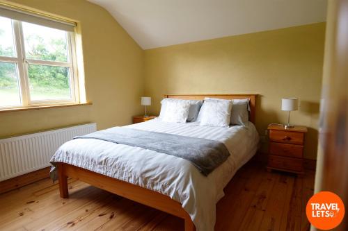 a bedroom with a large bed and a window at 5BR Farmhouse By Travel Lets Holiday Rentals Donegal in Carrigart