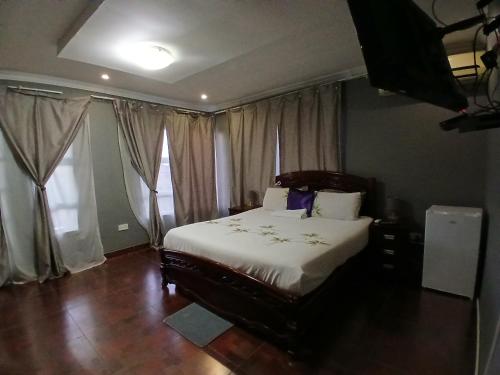 a bedroom with a bed with white sheets and windows at Kimberland Guest House Block 10 in Gaborone
