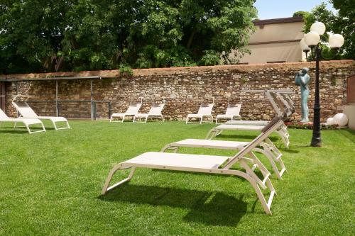 a row of white chairs sitting in the grass at Hotel Indigo Verona - Grand Hotel Des Arts by IHG in Verona