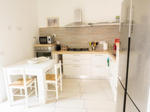 a white kitchen with a white table and a counter at Casa Vacanze L'Agrumeto in Milis