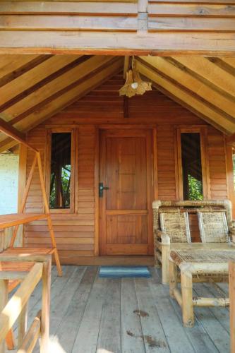 a porch of a wooden cabin with a wooden door at Bintang Homestay in Tetebatu