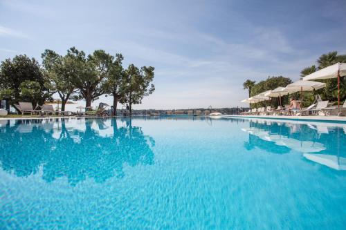 サロにあるHotel Spiaggia d'Oro - Charme & Boutique - Garda Lake Collectionの青い水とパラソル付きの大型スイミングプール