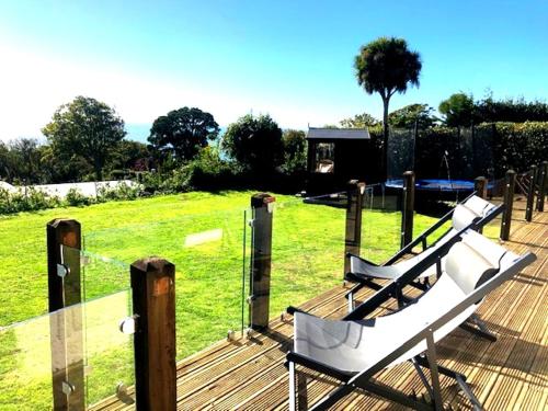 two white benches sitting on a deck near a field at Coastal retreat with stunning sea views in Isle of Wight