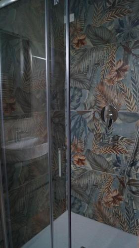 a shower with a glass door with a floral wallpaper at Terra Vitale in Cava deʼ Tirreni