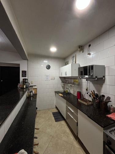 モンテビデオにあるMontevideo Chic Hostelのキッチン(黒いカウンタートップ、白い電化製品付)