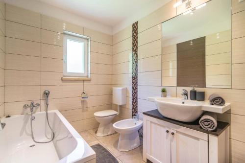 a bathroom with a tub and a sink and a toilet at Villa Zupan by Villa Plus in Vranići