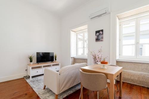 a living room with a couch and a tv and a table at Bright Flat in Historic Foz House by HostWise in Porto
