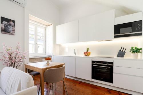 a kitchen with white cabinets and a table and chairs at Bright Flat in Historic Foz House by HostWise in Porto