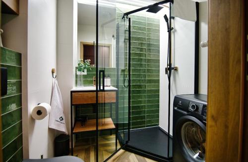 a bathroom with a glass shower and a washing machine at Comfortable apartment, sauna Żywiec Lake in Zarzecze