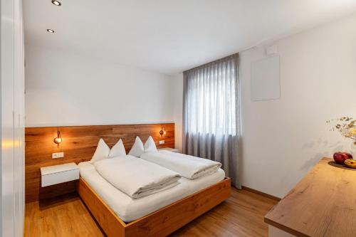 a bedroom with a large bed with white sheets at Appartement Sonnlicht Pfalzen in Falzes