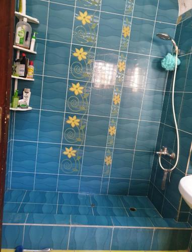a bathroom with a blue tiled wall with yellow flowers at Ma Sou in El Alamein