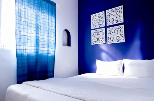 a bedroom with a white bed and a blue wall at Village Susegat Beach Resort in Morjim
