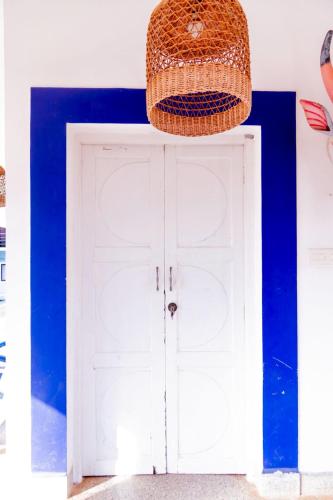 a wicker basket hanging over a white door with blue walls at Village Susegat Beach Resort in Morjim