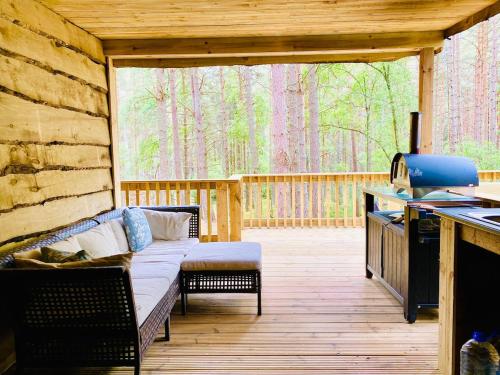 a screened in porch with a couch on a deck at Treetops at Wildwoodz Off grid treehouse No electricity in Allangrange Station