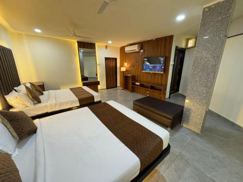 a hotel room with two beds and a flat screen tv at Hotel Shivtara in Nānded