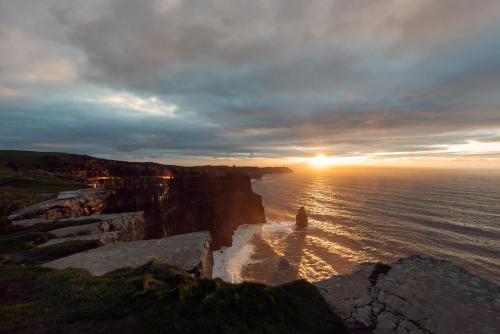 a sunset at the edge of a cliff over the ocean at The Turning of The Tide in Fanore