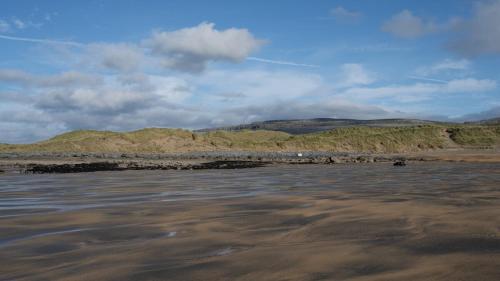 a beach with a body of water with mountains in the background at The Turning of The Tide in Fanore
